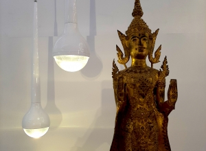 Zwei tropfenförmige Leuchten, neben einer goldenen Statue von einem indischen Budda